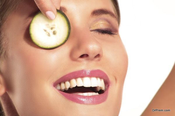 Young beautiflul smiling girl applying a cucumber beauty treatme