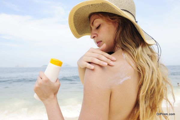 woman applying suntan lotion at the beach smiling