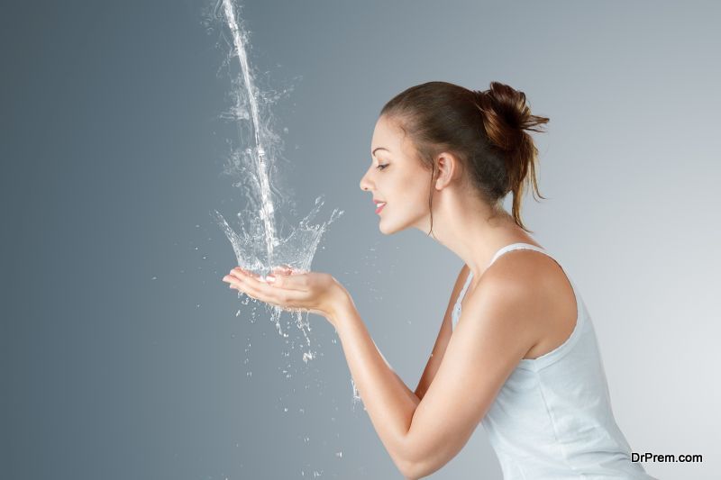 A young woman washing her face with flowing water