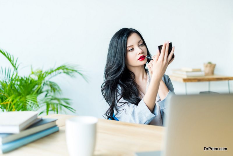 businesswoman applying lipstick at workplace