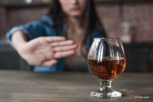 Young female alcoholic social problems sitting at table refusal of alcohol say no to addiction close-up